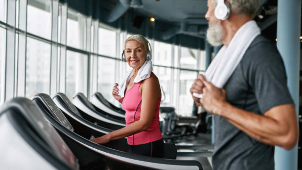 Elderly couple working out on treadmill in fitness center stock photo
