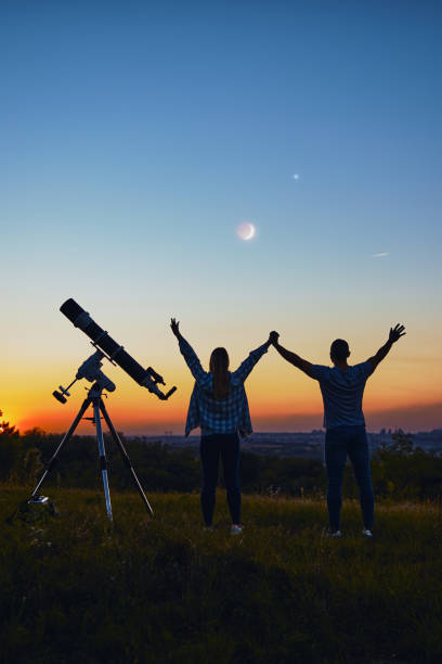 istock Couple stargazing together with a astronomical telescope. 1347205894