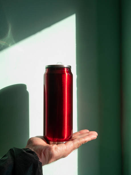 istock Red thermo can bottle in male hands against wall with harsh shadow.Hot tea coffee drinking in cold autumn winter weather 1347206078