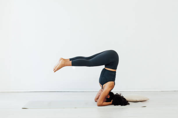 gymnaste asana de yoga féminine se tient sur sa tête - équilibre sur les mains photos et images de collection
