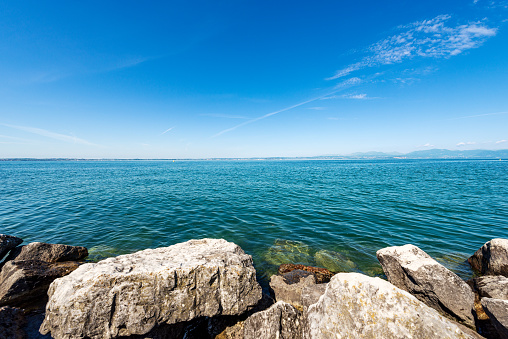 Lake Garda (Lago di Garda) in front of the small village of Lazise, tourist resort in Verona province, Veneto, Italy, Europe. On the horizon the coastline of Lombardy.