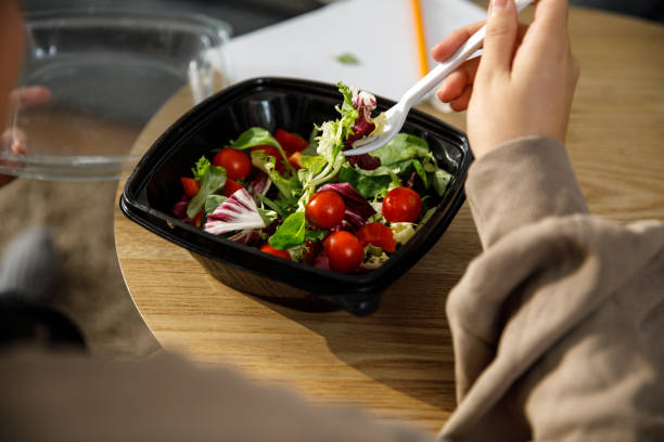 istock Young woman eating a takeaway salad with a plastic fork 1347208362