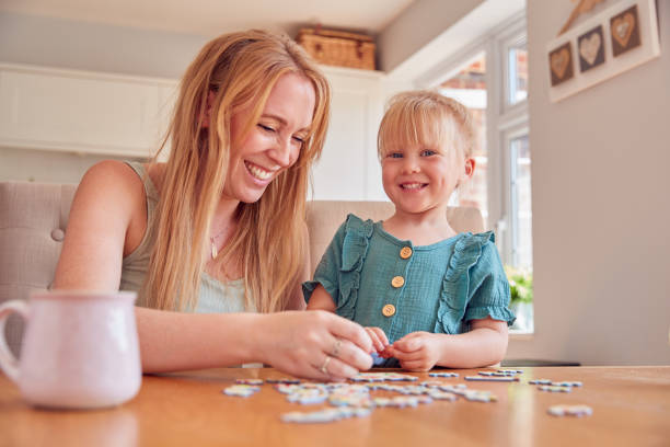 istock Mother And Daughter Having Fun Sitting At Table At Home Doing Jigsaw Puzzle Together 1347209619