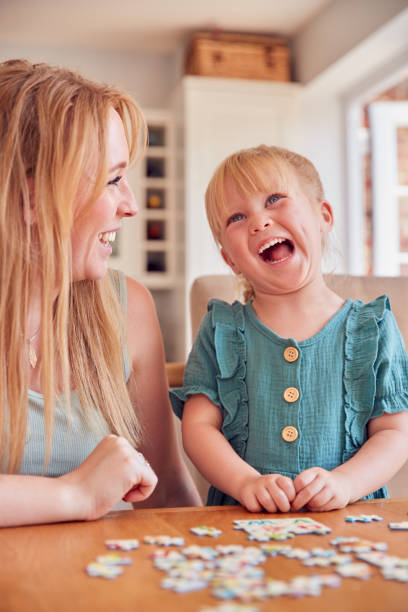 istock Mother And Daughter Having Fun Sitting At Table At Home Doing Jigsaw Puzzle Together 1347209668