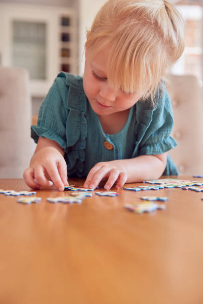 istock Young Girl Having Fun Sitting At Table At Home Doing Jigsaw Puzzle 1347209669