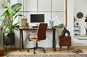 Creative workspace composition of modern masculine home office interior with black industrial desk, brown leather armchair, laptop, vintage record player and stylish personal accessories. Template.