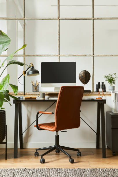 Creative workspace composition of modern masculine home office interior with black industrial desk, brown leather armchair, laptop, vintage record player and stylish personal accessories. Template. Creative composition of modern masculine home office workspace interior with black industrial desk, brown leather armchair, pc and stylish personal accessories. Template. home office chair stock pictures, royalty-free photos & images