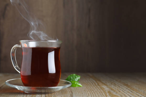 istock Glass cup of aromatic black tea on wooden table, space for text 1347213208