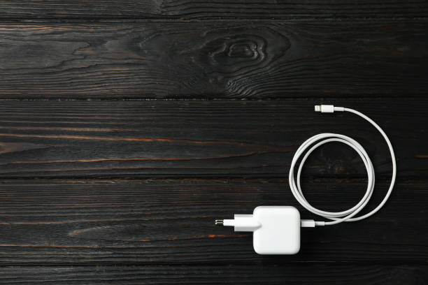 istock White charging cable and adapter on black wooden table, top view. Space for text 1347213261