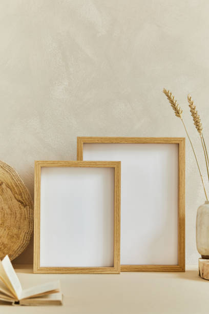 istock Stylish cozy interior design composition with mock up poster frame, natural materials as wood and marble, dry plants and personal accessories. Neutral beige colors, template. 1347215460