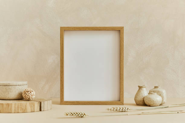 istock Stylish composition of cozy minimalistic interior design with mock up poster frame, natural materials as wood and marble, dry plants and personal accessories. Neutral beige colors, template. 1347216024