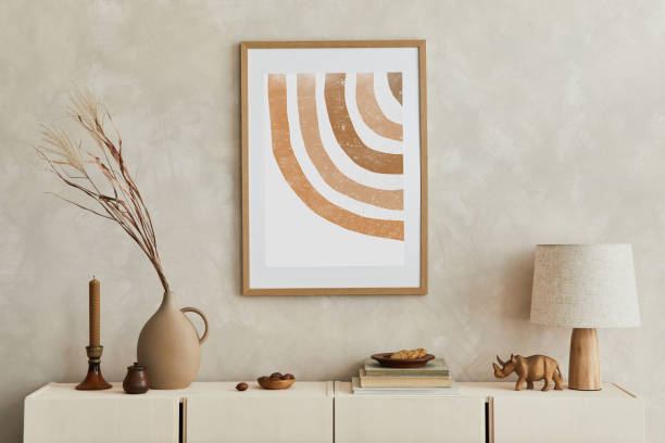 istock Creative composition of stylish living room interior with mock up poster frame, beige commode, clay vases and stylish personal accessories. Pastel neutral colors. Template. 1347217991