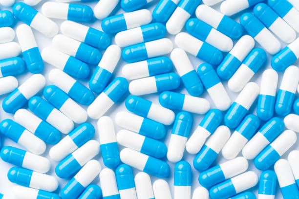 istock Blue and white capsule pills on white background 1347218240