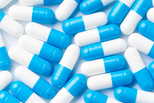 istock Blue and white capsule pills on white background 1347218421