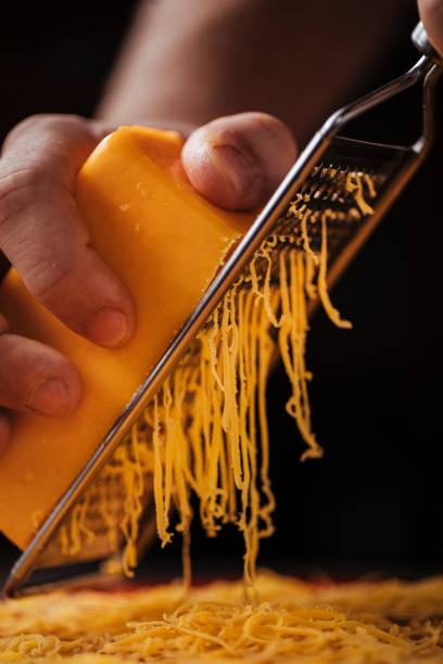 How can there be too much cheese? An unrecognisable persons hands grating cheese on a pizza grated stock pictures, royalty-free photos & images