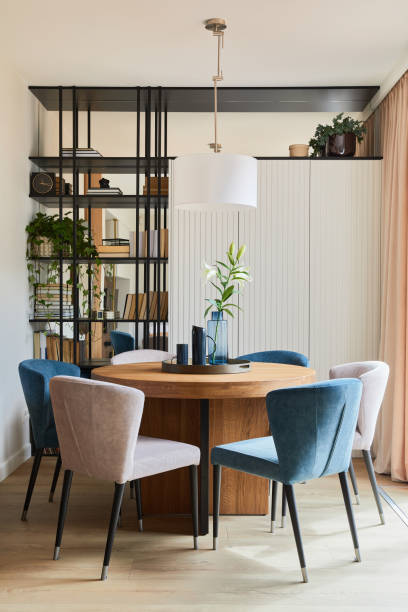 istock Stylish elegant dining room interior design composition with velvet armchairs, design rounded wooden table and beautiful personal accessories. Glamour interior design inspiration. Template. 1347220484
