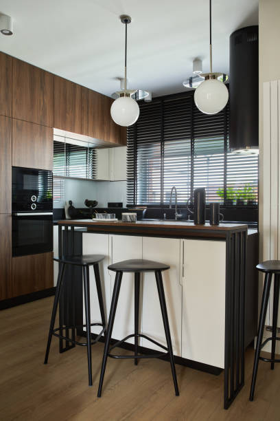 istock Stylish brown panel kitchen interior with biult-in kitchen, kitchen island, bar stools and personal accessories. Template. 1347220543