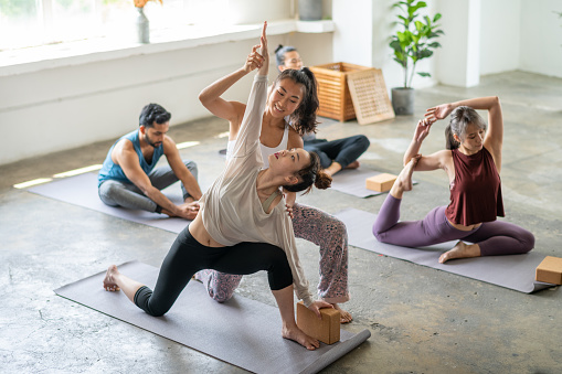 young asian female stretching in yoga class with yoga instructor in yoga studio stock photo