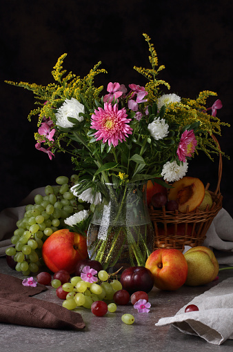 Studio still life with flowers, grapes, peaches and plums in retro style