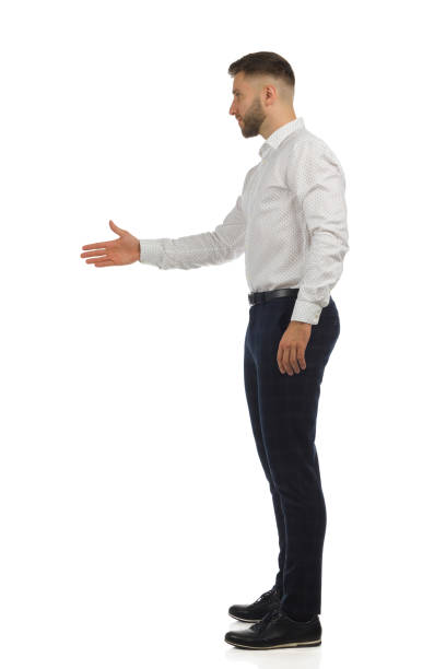 istock Elegant handsome man is standing with outstretched hand to greet. Side view, full length isolated. 1347222047
