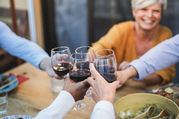 les personnes âgées s’amusent à applaudir avec du vin au dîner sur le patio - concentrez-vous sur le visage féminin - dining senior adult friendship mature adult photos et images de collection