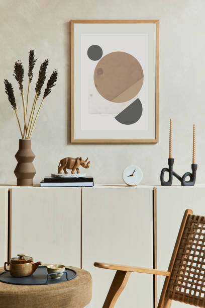 istock Creative and modern beige living room interior composition with mock up poster frame, beige wooden sideboard and boho inspired accessories. Template. 1347224238