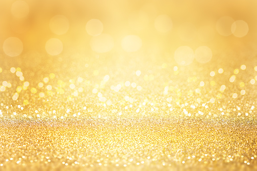 Gold glitter background. Abstract Christmas background with bokeh and defocused lights. Soft focus
