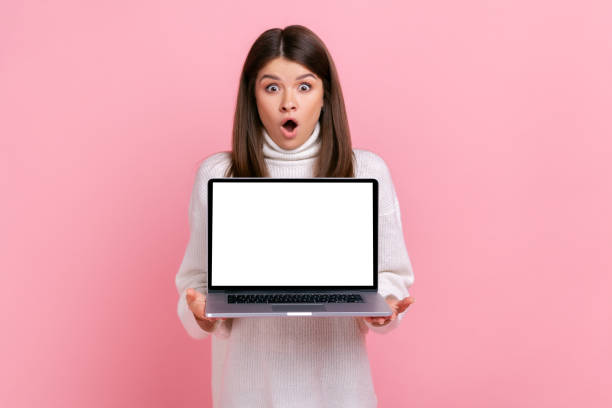 istock Astonished female holding notebook with empty display in hands, looking at camera with open mouth. 1347228218