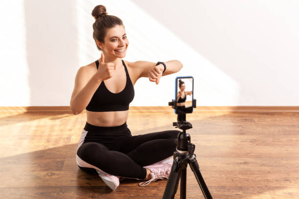 istock Fitness instructor broadcasting online workout, checking results with tracker, showing thumb up. 1347228531