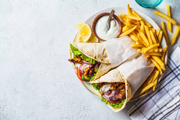 Chicken gyros with vegetables, french fries and tzatziki sauce on plate. Greek food concept. Chicken gyros with vegetables, french fries and tzatziki sauce on a plate, top view. Greek food concept. mediterranean food photos stock pictures, royalty-free photos & images