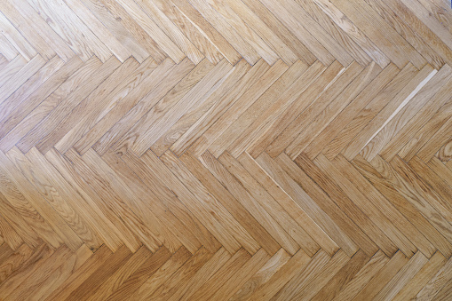 Parquet with herringbone background. Wooden floor with a chevron pattern in the living room of the designer interior. High quality photo