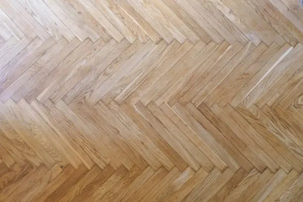 Photo of Parquet with herringbone background. Wooden floor with a chevron pattern in the living room of the designer interior