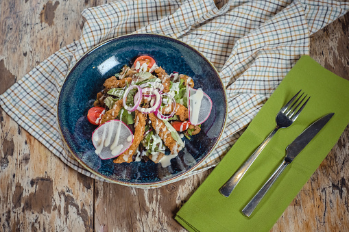 Salad with fried chicken breast on wooden background
