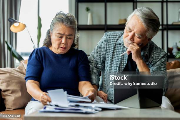 Serious Stressed Asian Senior Old Couple Worried About Bills Discuss Unpaid Bank Debt Paper Sad Poor Retired Family Looking At Tablet Counting Loan Payment Worry About Money Problem Stock Photo - Download Image Now