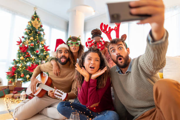 Friends having fun taking selfies while celebrating Christmas at home stock photo