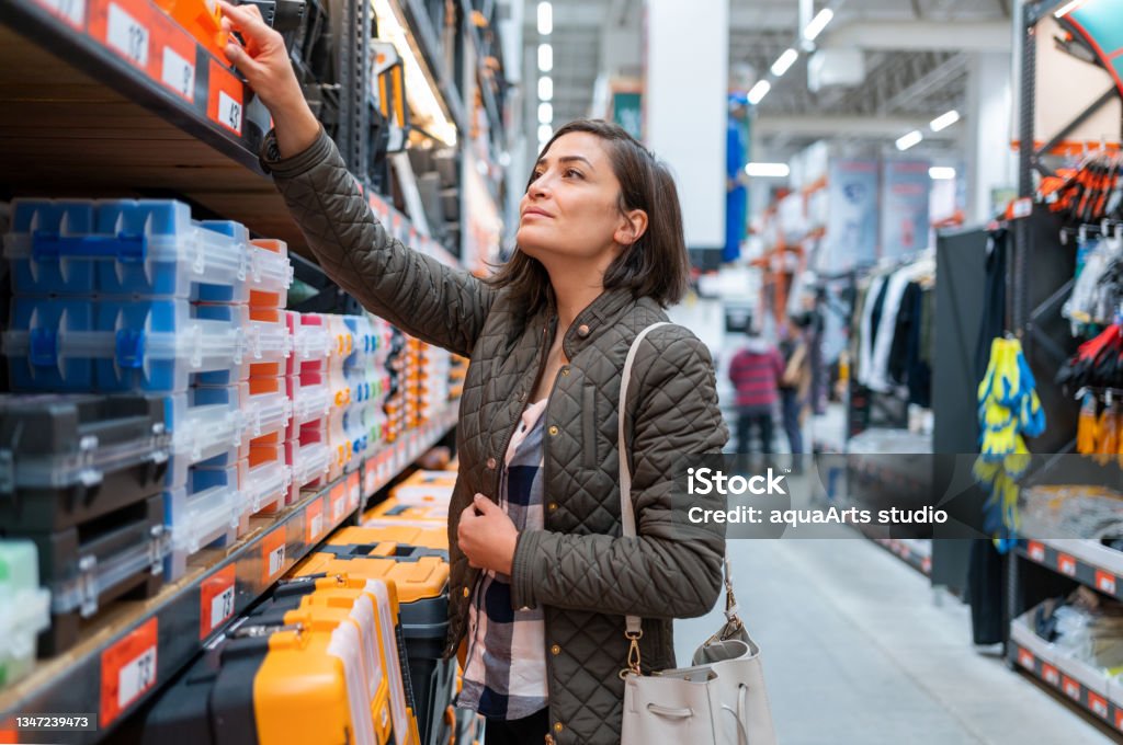 Shopping At Construction Store Woman Choosing Materials in Construction Store Shopping Stock Photo