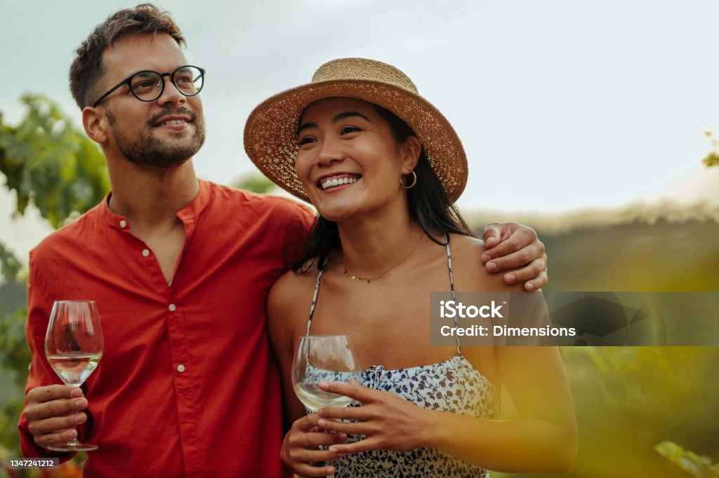 As good as nature intended Diverse couple enjoying a glass of wine while walking through the vineyard Wine Stock Photo