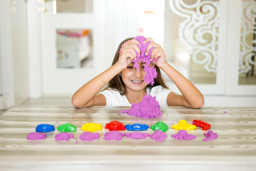 Happy little girl playing with kinetic sand