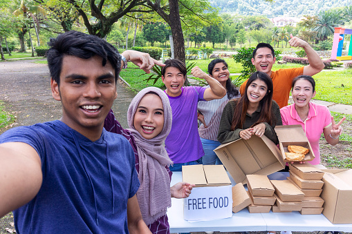 Multi-ethnic group of volunteers taking selfie while sorting donations for food bank
