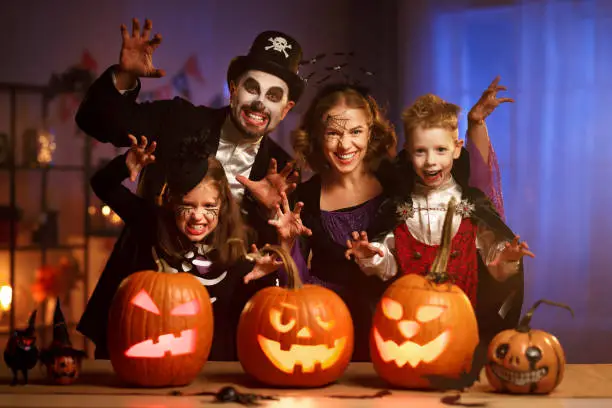 Photo of Young family mother father and children in Halloween costumes celebrating all hallows eve at home