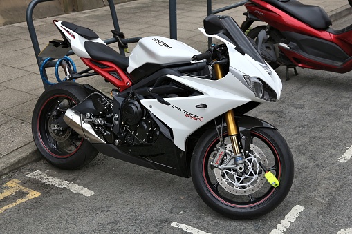 White Triumph Daytona 675 R motorcycle parked in Leeds. It's a three cylinder sports bike of British brand Triumph Motorcycles.