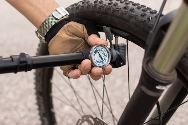 человек, проверяющий давление в шинах велосипеда, надувающий воздух ручным насосом - bicycle bicycle pump inflating tire стоковые фото и изображения