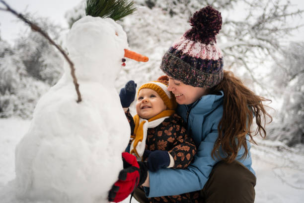 istock Joyful mother and her toddler son making a snowman 1347245560