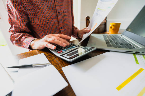 homme âgé vérifiant les factures à la maison - calculer photos et images de collection