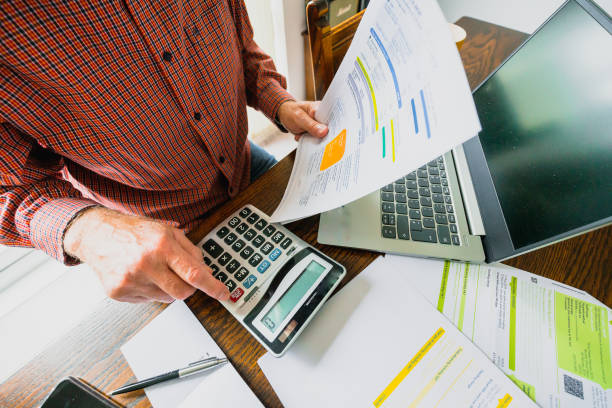 senior man checking bills at home - inflation imagens e fotografias de stock