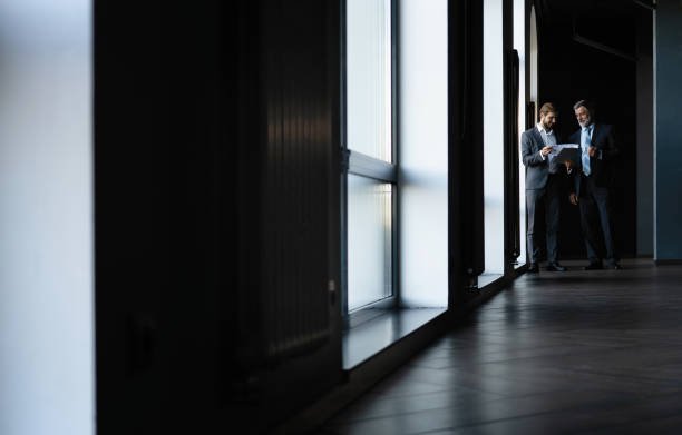istock Two colleagues communicating in corridor, partners walking in the modern office 1347247074