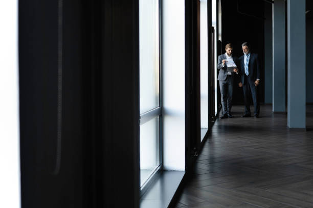 istock Two colleagues communicating in corridor, partners walking in the modern office 1347247083