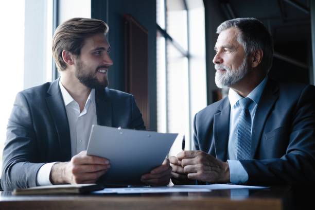 istock Senior and junior businessman discuss something during their meeting, office background. 1347247151