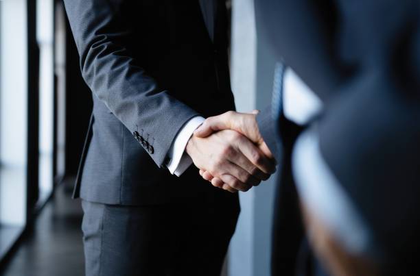 uomini d'affari che si stringono la mano, terminando una riunione. - handshake foto e immagini stock