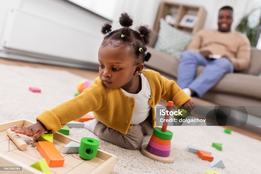 african baby girl playing with toy blocks at home childhood and people concept - little african american baby girl playing with toy blocks at home Playing Stock Photo